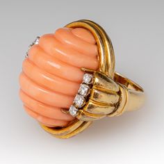 This wonderful cocktail ring is centered with an oval shaped natural coral with a carved fluted design that is set with four-prongs. The coral is bordered to each side with four (4), prong set, round brilliant cut diamonds. The ring measures 28.8mm at the top, rises 18.0mm above the finger, tapering to 2.9mm wide and 1.2mm thick at the base of the shank. It is currently a size 4.75 and is currently unpolished with a rich and lovely patina. Elegant Oval Coral Rings, Elegant Coral Oval Rings, The Coral, Natural Coral, Pink Coral, Round Brilliant Cut Diamond, Cocktail Ring, Brilliant Cut Diamond, Cocktail Rings