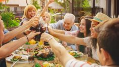 a group of people toasting at a table with food and drinks in front of them