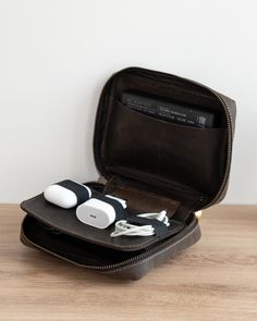 an open case with two ear buds in it on a wooden table next to a white wall