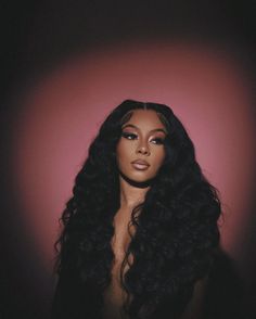 a woman with long black hair standing in front of a red wall