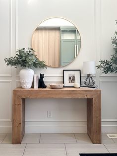 a wooden table topped with a mirror next to a plant and potted plant on top of it