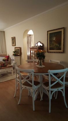 a dining room table with four chairs and a couch in the backround next to it