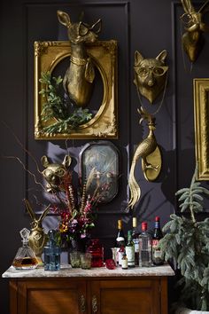 there are many items on the table in front of the wall with gold deer heads