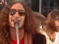 a man with long hair and sunglasses singing into a microphone