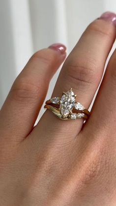 a woman's hand with a diamond ring on top of her finger and an engagement band