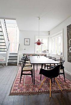 a dining room table with chairs and a rug on the floor in front of it