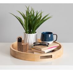 a wooden tray with a plant, book and cell phone on it next to a pair of glasses