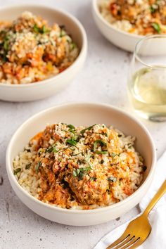 three bowls filled with rice and meat on top of a table next to a glass of water