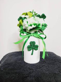 a st patrick's day bouquet in a white vase with green ribbon and shamrocks