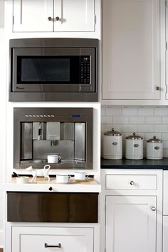 a microwave oven sitting on top of a kitchen counter next to white cabinets and drawers