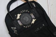 "Hand Embroidered Fjallraven Kanken No. 2 Black Backpack - Fjallraven's special Kanken No. 2 in Black with Black Leather Trimming This listing includes 1 Fjallraven Kanken No. 2 Black Backpack, in the size of your choosing, custom hand embroidered! Step 1: Pick a size Kanken No. 2 Black (Mini, Full, Laptop 15\") Step 2: Choose an embroidery style. If you would like a custom design, choose the 'custom' variation. If you would like a name with a floral wreath please choose the 'floral name' variat Black Kanken Embroidery, Kanken No.2, Kanken Embroidery Black, Black Embroidered Standard Backpack, Embroidered Black Travel Backpack, Black Embroidered Travel Backpack, Black Embroidered Backpack, Black Kanken Backpack, Black Hand Embroidery