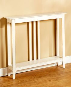 a white wooden shelf sitting on top of a hard wood floor next to a wall