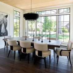 a dining room table with white chairs and a large painting on the wall behind it