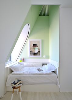 a bed room with a neatly made bed next to a window and a mirror on the wall