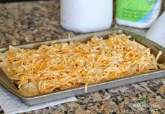 a baking pan filled with shredded cheese and tortilla chips next to a roll of toilet paper