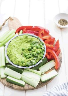 a wooden cutting board topped with vegetables and dip