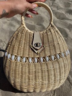 a person holding a wicker purse on the beach