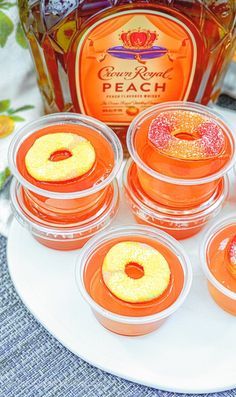 four orange jello shots sitting on top of a white plate next to a bottle