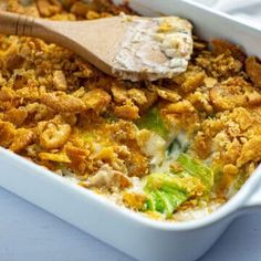 a casserole dish with bread crumbs and vegetables in it, topped with a wooden spoon