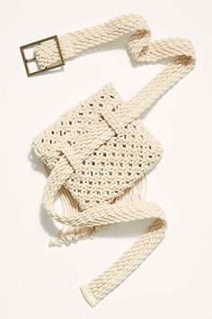 a crocheted bag is laying on the floor with a belt around it's neck