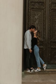 a man and woman kissing in front of an ornate door