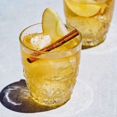 two glasses filled with drinks sitting on top of a white table next to each other