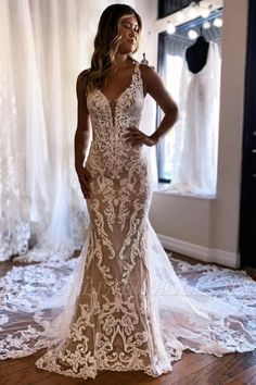 a woman standing in front of a window wearing a wedding dress