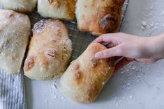 a person is picking up some bread from a cooling rack