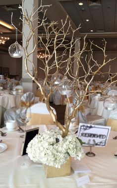 there is a vase with flowers and branches in it on the table at this wedding reception