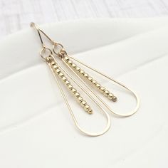 Add a touch of glam to any outfit with Harley - Gold & Gold earrings! These long teardrop earrings feature 14k gold filled construction and stunning gold beads. A must-have accessory for any fashionable individual looking to elevate their style game. Shine on, babe! Approximately 2.25” long Made with 14k Gold Filled Polished to a high shine Handmade in Montana Sent in a ribboned gift box with polishing cloth African Turquoise, Jewelry Packaging, Christmas Shopping, Gold Beads, Teardrop Earrings, Gold Filled, Gold Earrings, Sterling Silver, Beads