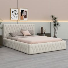 a white bed sitting on top of a hard wood floor next to a wall with pictures above it