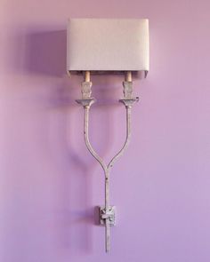 a wall mounted light with a white shade on it's head and two arms