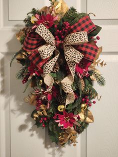 a christmas wreath on the front door with leopard print bow and poinsettis