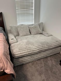 a bed that is in the corner of a room next to a window with blinds