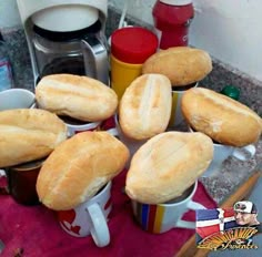 several coffee cups filled with bread on top of a red towel next to a counter