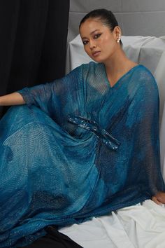 Jade blue kaftan with blotch print, lurex stripes and placement hand embroidery. Comes along with an inner slip.
Components: 2
Pattern: Hand Embroidery, Print
Type Of Work: Blotch, Geometric
Neckline: V Neck
Sleeve Type: Batwing Sleeves
Fabric: Lurex, Nokia Silk
Color: Blue
Other Details: 
Note: Only the outfit mentioned in the description is being sold
Occasion: Resort - Aza Fashions Blue Embellished Kaftan For Party, Embellished Blue Kaftan For Party, Blue V-neck Kaftan For Party, Blue Sequined Kaftan For Party, Blue Sequined Kaftan For Eid, Blue Sequined Party Kaftan, Blue Sequined Kaftan For Festive Occasions, Blue V-neck Kaftan For Evening, Festive Blue Sequined Kaftan