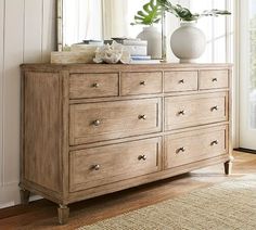 a wooden dresser sitting in front of a mirror