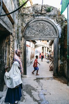 two women are walking through an alley way