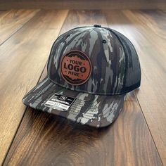 "Your Personalized Camo Leather Patch Hat. Make your business stand out with a high-quality leather patch adding your business logo or image engraved. PRODUCT DETAILS -------------------------- ~ Camo Richardson, Yupoong trucker style snapback hats ~ Add your logo on our high quality 100% genuine leather patch hats ~ Hat Color Options: Black, Navy, Heather Gray / Black, Charcoal / White, Navy / White, Charcoal / Black, Black / Charcoal, Loden / Black ~ Leather Patch Colors: Saddle Tan ~ Please g Brown Snapback Hat With Custom Logo For Outdoor, Outdoor Leather Hat With Custom Logo, Brown Snapback Hat With Custom Logo, Brown Custom Logo Trucker Hat With Flat Bill, Cattle Tags, Richardson Hats, Leather Patch Hat, Patch Hats, Patch Hat