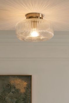 a close up of a ceiling light with a painting on the wall in the background