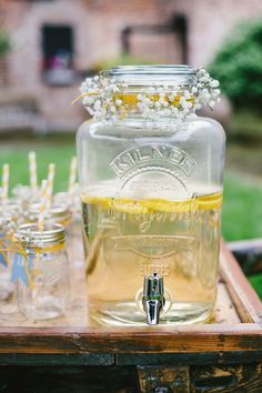 a mason jar filled with lemonade sitting on top of a wooden tray next to glasses