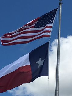 two american and texas flags flying side by side in front of a cloudy blue sky