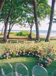 an outdoor ceremony setup with chairs and flowers in the foreground, overlooking the ocean