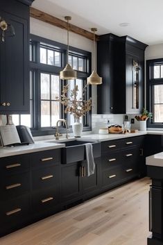 a large kitchen with black cabinets and white counter tops is pictured in this image, there are two chandeliers hanging from the ceiling