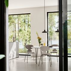 a dining room table with four chairs and a vase on the table next to it