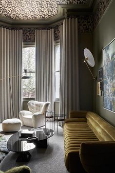 a living room filled with furniture next to a window covered in curtains and drapes