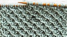 a close up view of a crocheted blanket with two knitting needles on it