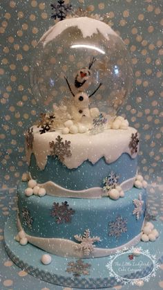 there is a snow globe on top of a cake that has snow flakes all over it