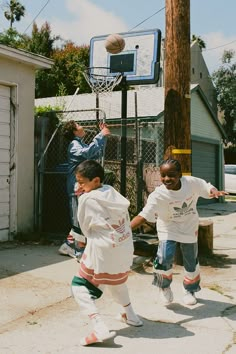 two young boys playing basketball in the street