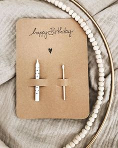 a pair of white candles sitting on top of a piece of paper next to a string